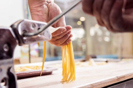 Chef rolling dough with a pasta machine. Pasta maker machine.