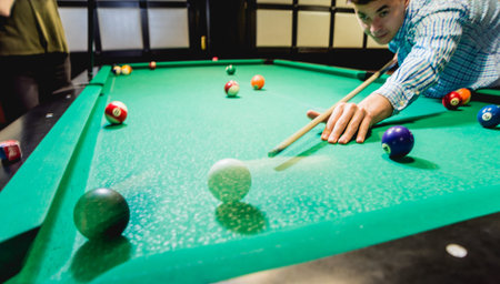 Young man trying to hit the ball in billiard.