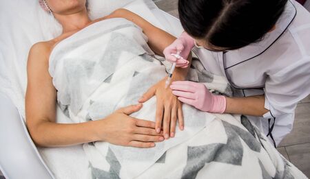 The doctor cosmetologist makes the arms injections procedure.の写真素材
