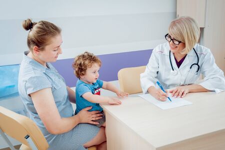Friendly doctor pediatrician with patient child at clinicの写真素材