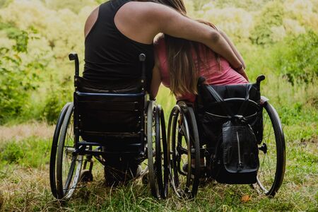 Handicapped couple resting in the forest near lake. Wheelchairs in the forest on the natural background. Camping. Summertimeの写真素材
