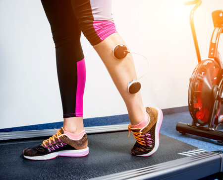 Young sports woman with electrostimulator on the muscles of the legs. Fitness training with an...