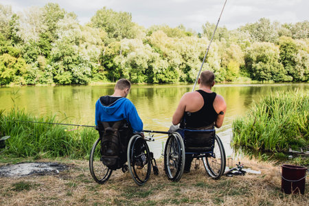 Handicapped men fishing at a lake. Wheelchair. Camping. Summertimeの写真素材