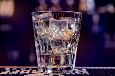 Alcoholic cocktail with ice at wooden bar counter. Restaurant. Background