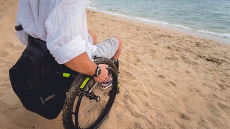 Disabled man in a wheelchair on the beach. Concept backgroundの写真素材
