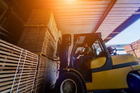 Forklift loader load lumber into a dry kiln. Wood drying in containers. Industrial conceptの写真素材