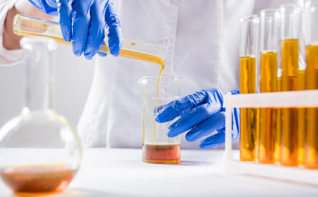 Scientist pouring organic oil. Beauty and cosmetics sciences. Laboratory equipment. White background
