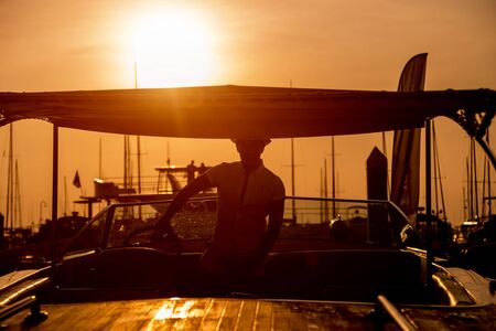 Young man on sailing yacht. Hands hold steering wheelの写真素材