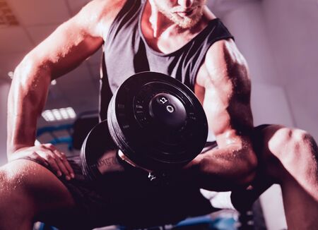 Handsome muscular man working out with dumbbells.の写真素材