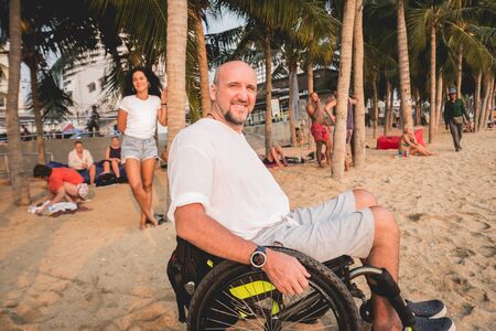 Disabled man in a wheelchair on the beach.の写真素材