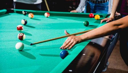 Young woman trying to hit the ball in billiard. Billiard room on the background.
