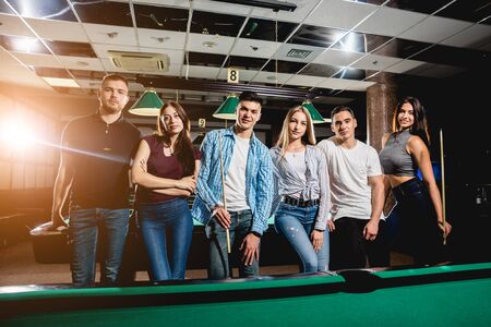 Group of young cheerful friends playing billiards.の写真素材