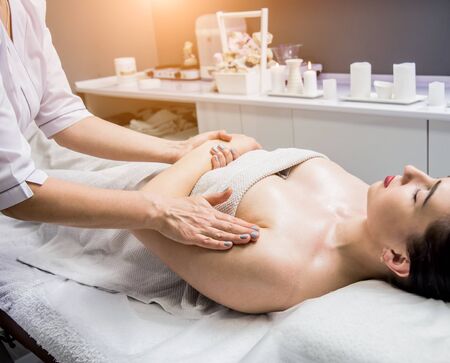 Beautiful young woman enjoying massage in spa salon. Cosmetologyの写真素材
