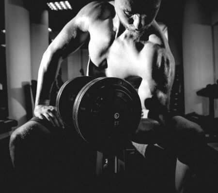 Handsome muscular man working out with dumbbells.の写真素材