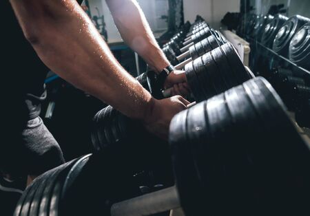 Handsome muscular man working out with dumbbells.の写真素材