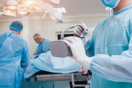 Doctor in a surgical room with virtual reality glasses on the backgroundの写真素材