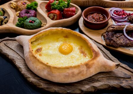 Khachapuri with cheese, vegetables and eggs. Georgian national cuisine. Restaurant. Backgroundの写真素材