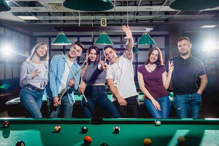 Group of young cheerful friends playing billiards.の写真素材