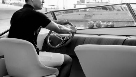 Young man on sailing yacht. Hands hold steering wheelの写真素材