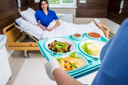 Nurse in medical coat is holding a tray with breakfastの写真素材