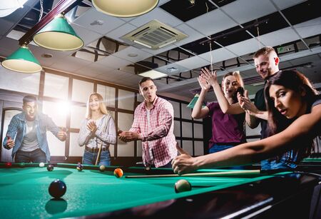 Group of young cheerful friends playing billiards.の写真素材