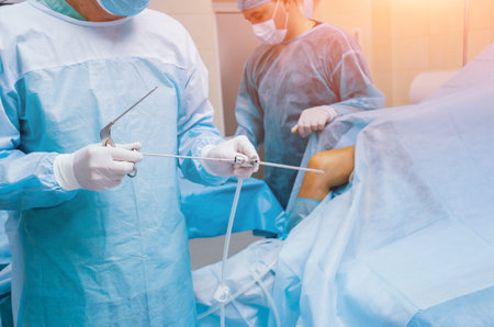 Arthroscope surgery. Orthopedic surgeons in teamwork in the operating room with modern arthroscopic...