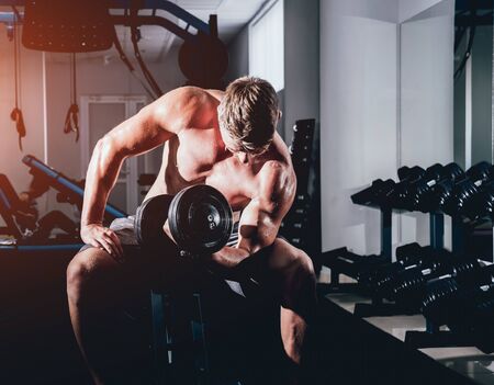 Handsome muscular man working out with dumbbells.の写真素材