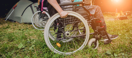 Disabled man resting in a campsite with friends. Wheelchair in the forest