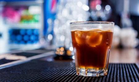 Alcoholic cocktail with ice at wooden bar counter. Restaurant.