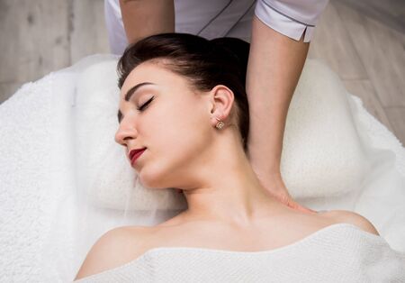 Beautiful young woman enjoying head massage in spa salon. Cosmetologyの写真素材