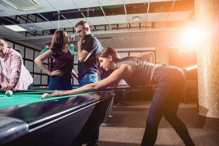 Group of young cheerful friends playing billiards.
