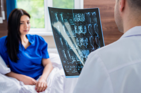 Traumatologist showing MRI film to patient in hospital.