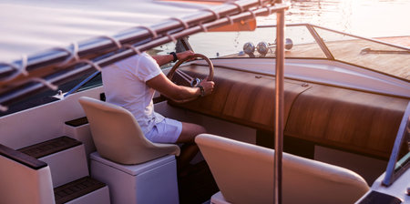 Young man on sailing yacht. Hands hold steering wheel