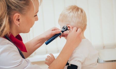 Doctor examines ear with otoscope in a pediatrician room. Medical equipmentの写真素材