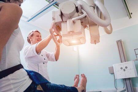 Radiologist and patient in a x-ray room. Classic ceiling-mounted x-ray system.の写真素材