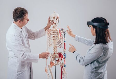 Doctor uses augmented reality goggles and human skeleton for teaching studentの写真素材