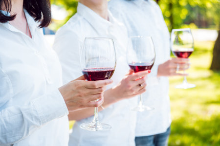 Young beautiful girls with glass of red wine in the park. Nature background