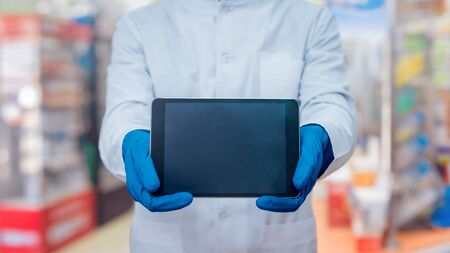 Doctor holding blank screen tablet computer. At the pharmacyの写真素材