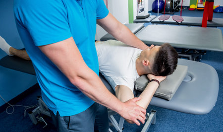 Rehabilitation therapy. Physiotherapist working with young male patient in the rehabilitation...