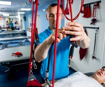 Physiotherapy. Suspension training therapy. Young man doing fitness therapyの写真素材