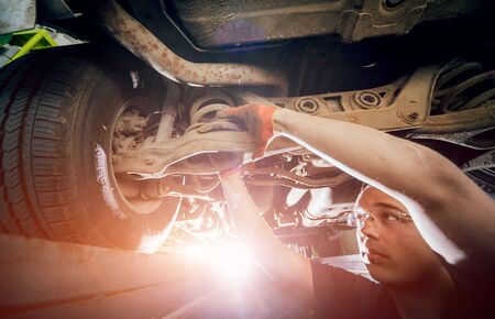 Car mechanic repair car suspension of lifted automobileの写真素材