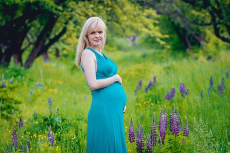 Beautiful pregnant woman with flowers in the park.の写真素材