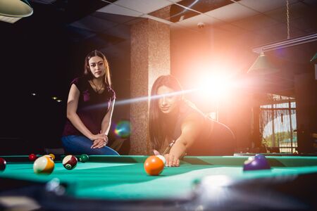 Group of young cheerful friends playing billiards.の写真素材