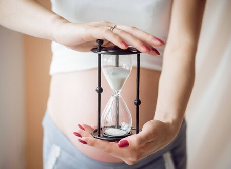 Young pregnant woman near a window. Light background.の写真素材