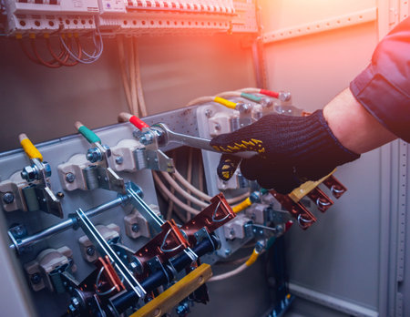 Electricians hands testing switches in electric box. Electrical panel with fuses and contactors....