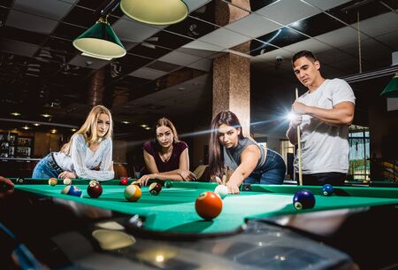 Group of young cheerful friends playing billiards.の写真素材