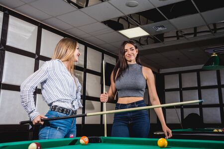 Two young women playing in billiard.の写真素材