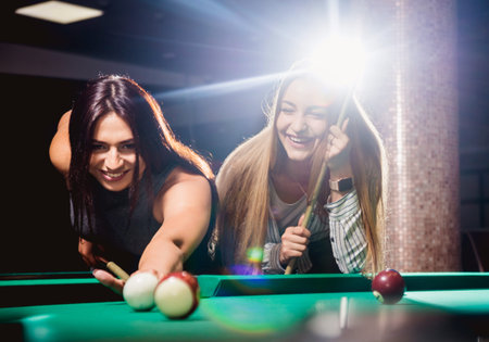 Two young women playing in billiard.