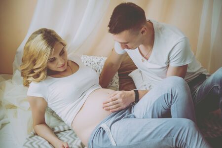Young pregnant woman and her husband. Waiting for baby.の写真素材