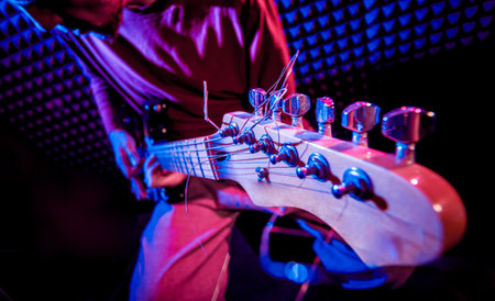 Young man playing on the guitar in sound recording studio. Modern background